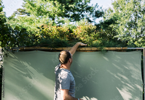 Sukkot: Man Covers Roof Of Sukkah With Branches photo