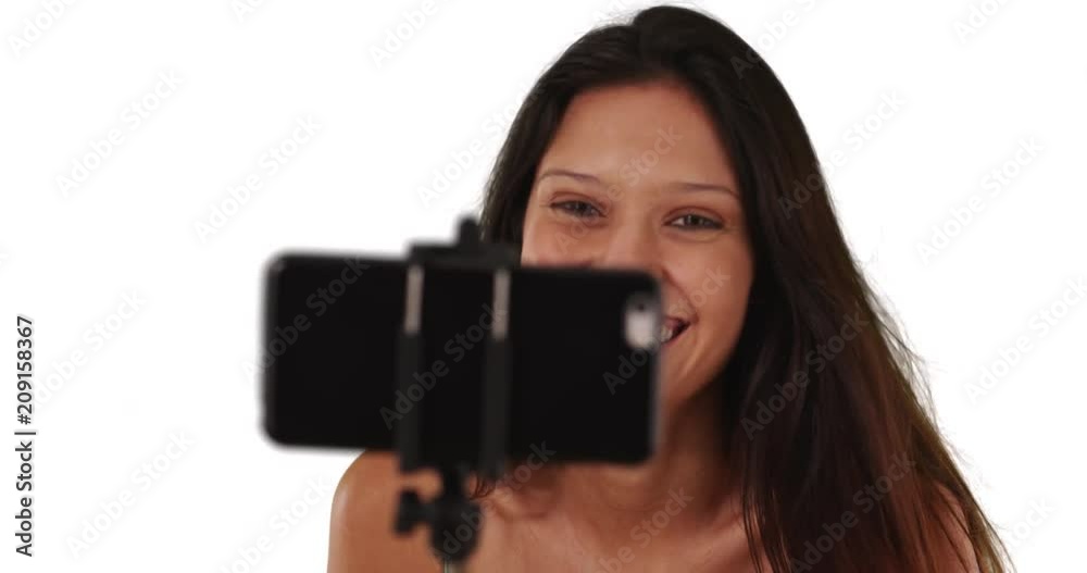 Close up of cute casual brunette girl using selfie stick on white background with copyspace, Young tourist woman taking fun pictures blowing kiss, 4k Close up of cute casual brunette girl using selfie stick on white background with copyspace, Young tourist woman taking fun pictures blowing kiss, 4k