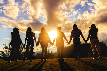silhouette of friends girls group standing at sunset time
