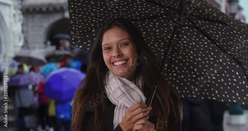 Happy millennial female on Venice city street with polka dot umbrella, Caucasian woman spinning her umbrella during rainstorm on busy street with tourism, 4k