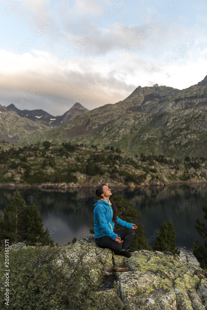 Female hiker meditating in an alpine scenery Female hiker meditating in an alpine scenery
