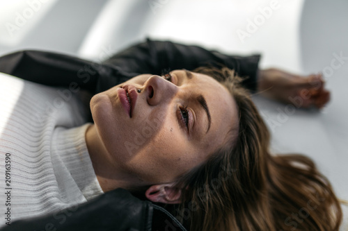 Young adult woman indoors studio with light patterns and shadows on face