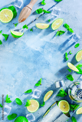 Fresh mojito cocktail ingredients, mint, lime and ice cubes on a gray stone background. Shaker and bar accessories flat lay. Summer drink concept with copy space.