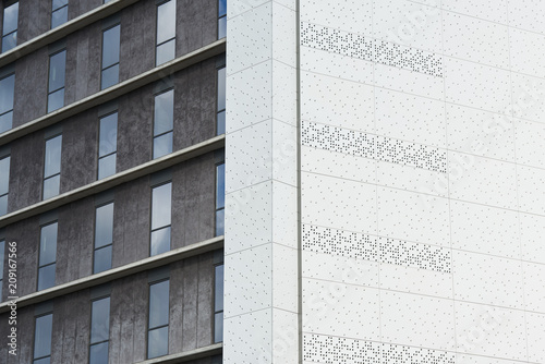 White textured building wall against grey block with windows.