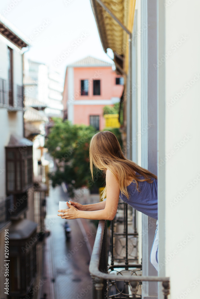 Woman having breakfast on the balcony, Granada, Spain. Woman having breakfast on the balcony, Granada, Spain.