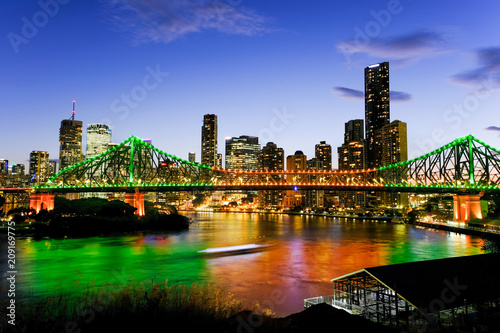 View of Brisbane lit up at dusk with a ferry passing under the Story Bridge © Matt Murray
