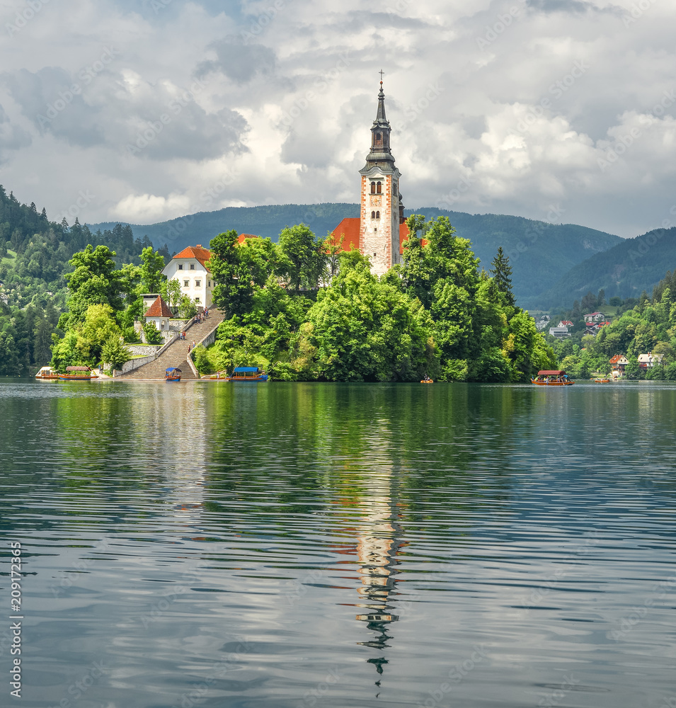 Bled, Slovenia - May 20, 2018:  Beautiful Lake Bled in the Julian Alps and Assumption of Mary Church, Bled Slovenia.   Mountains, Old church in the middle of the lake and dramatic sky.