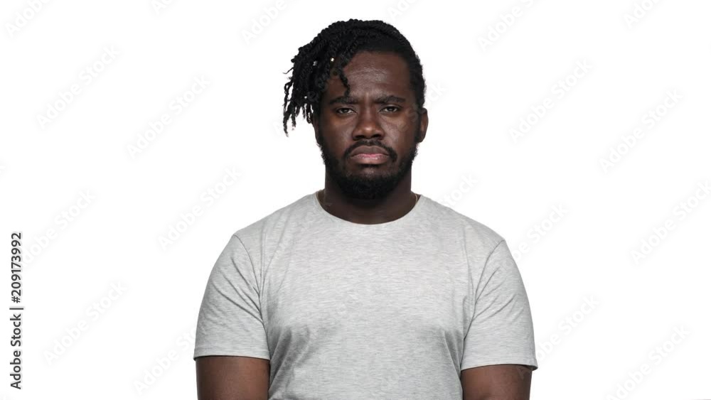 Portrait of severe bearded dark skinned guy in casual t-shirt with strict gaze asking to keep quiet putting index finger on lips, isolated over white background. Concept of emotions Portrait of severe bearded dark skinned guy in casual t-shirt with strict gaze asking to keep quiet putting index finger on lips, isolated over white background. Concept of emotions