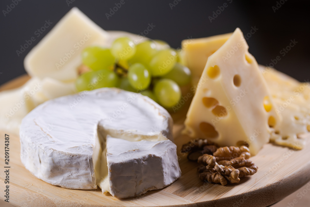 Different kinds of cheese on a plate with grapes and nuts