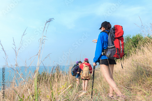 Group asian young women of hikers walking with backpack on a mountain blue sky. Traveler going camping. Travel Concept.