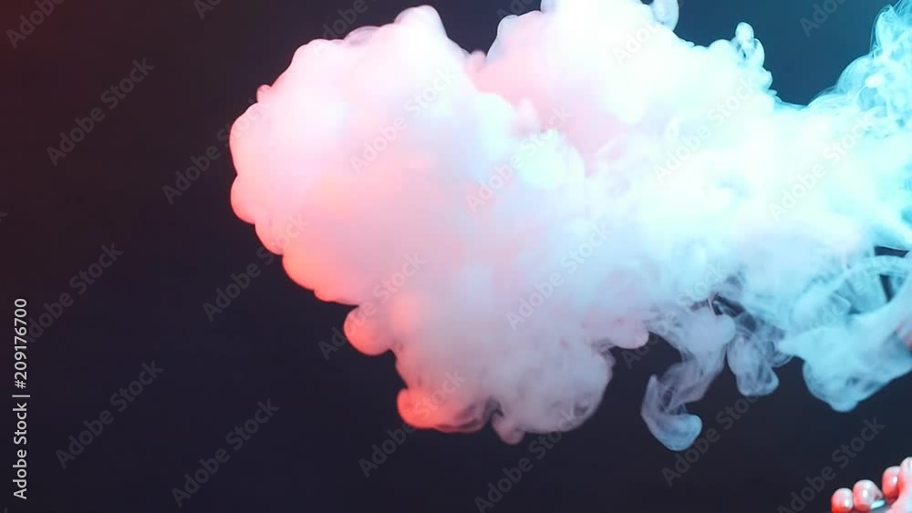 Young woman smokes electronic cigarette in color light. Night life and vape concept