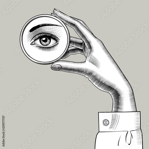 Female hand holding a round small mirror with a reflection of her eye