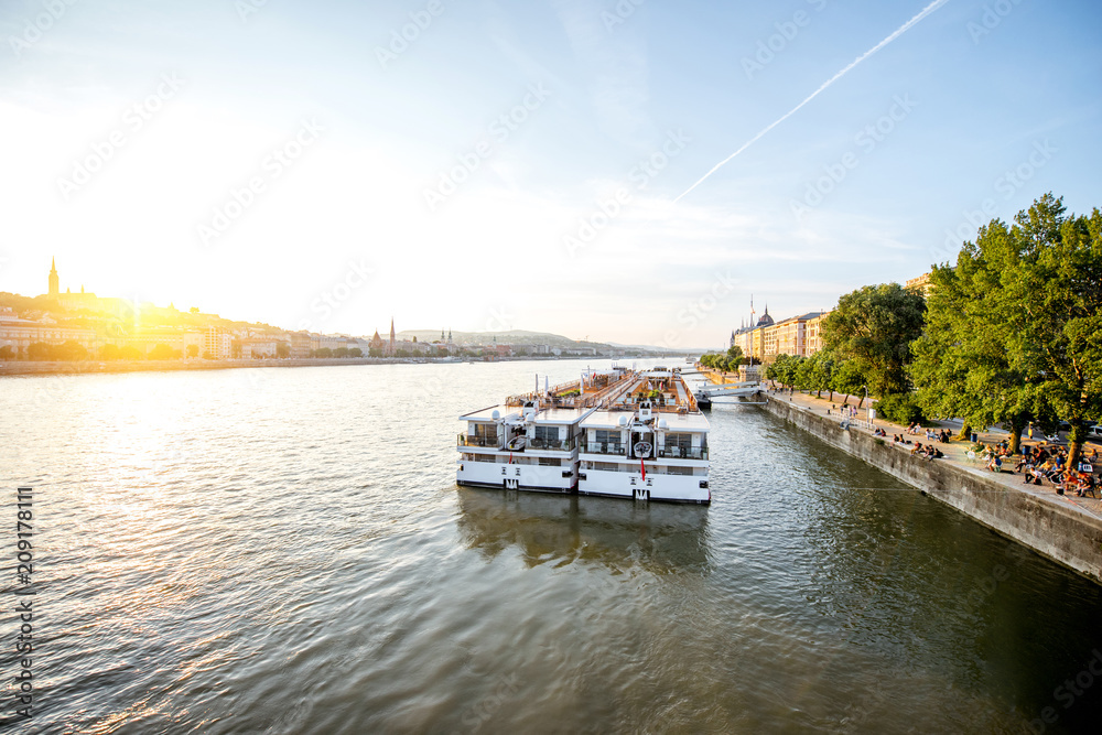 Fototapeta premium Landscape view on Danube river with tourist ship during the sunset in Budapest city, Hungary