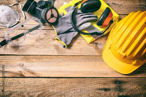 Construction safety. Protective hard hat, headphones, gloves and glasses on wooden background, copy space, top view photo