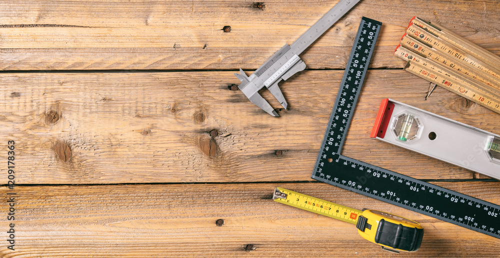 Carpentry. Measure tape, spirit level and rulers on wooden background, copy space, top view Carpentry. Measure tape, spirit level and rulers on wooden background, copy space, top view