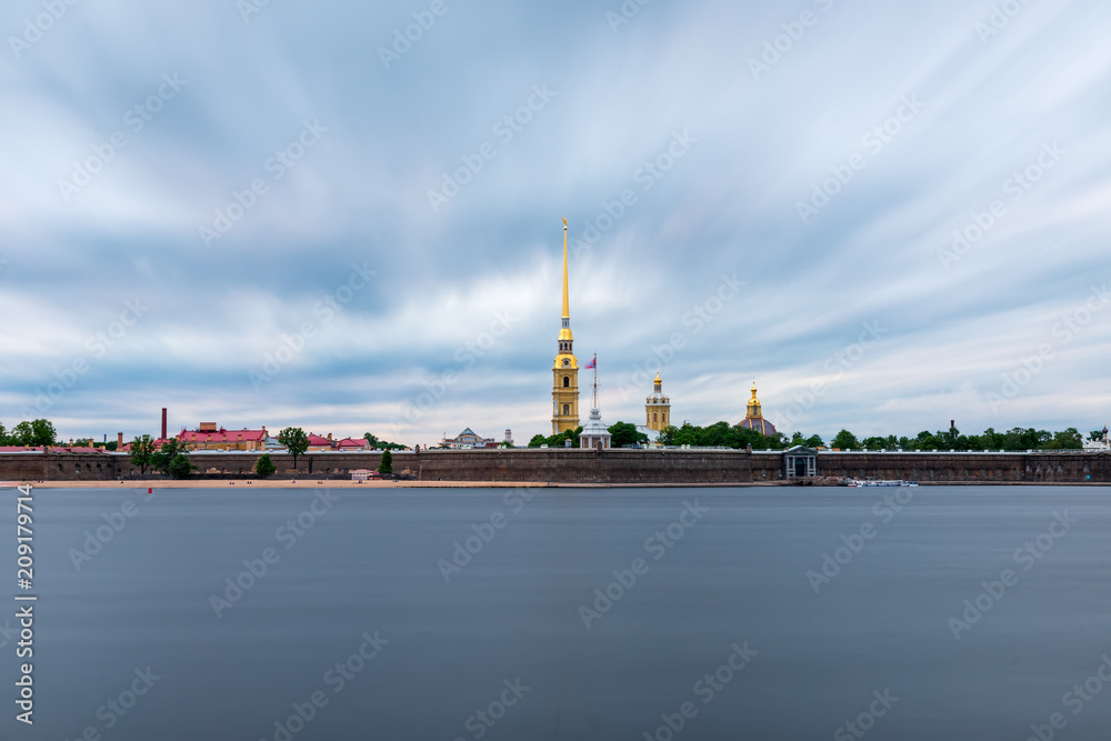 St Petersburg, Russia. Peter and Paul fortress with the Palace promenade, Petropavlovskaya krepost, white nights.Blue cloudy sky, dark water of the Neva river