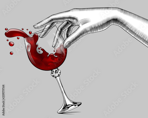 Female hand and a falling glass with splashed red wine