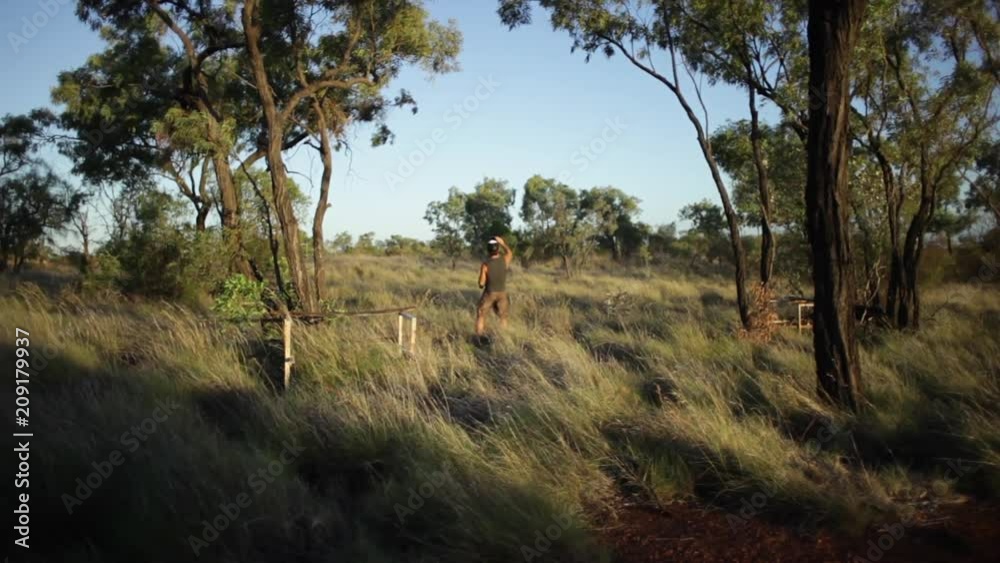 A steady long shot of a man wearing green standing on grass on a safari. A steady long shot of a man wearing green standing on grass on a safari.