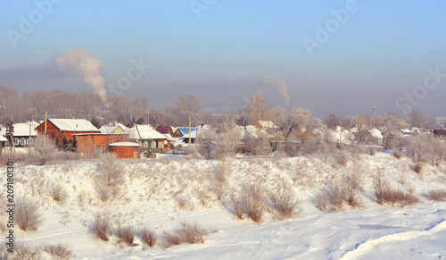 Winter landscape with village on the river bank.
