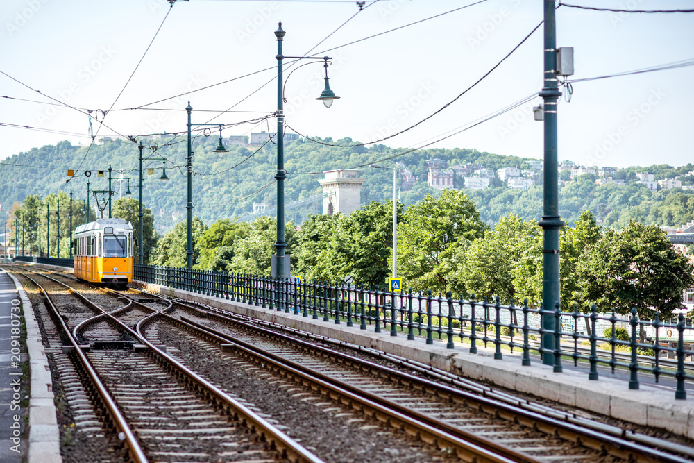 Railway with old yellow tram near the river during the morning light in Budapest city, Hungary