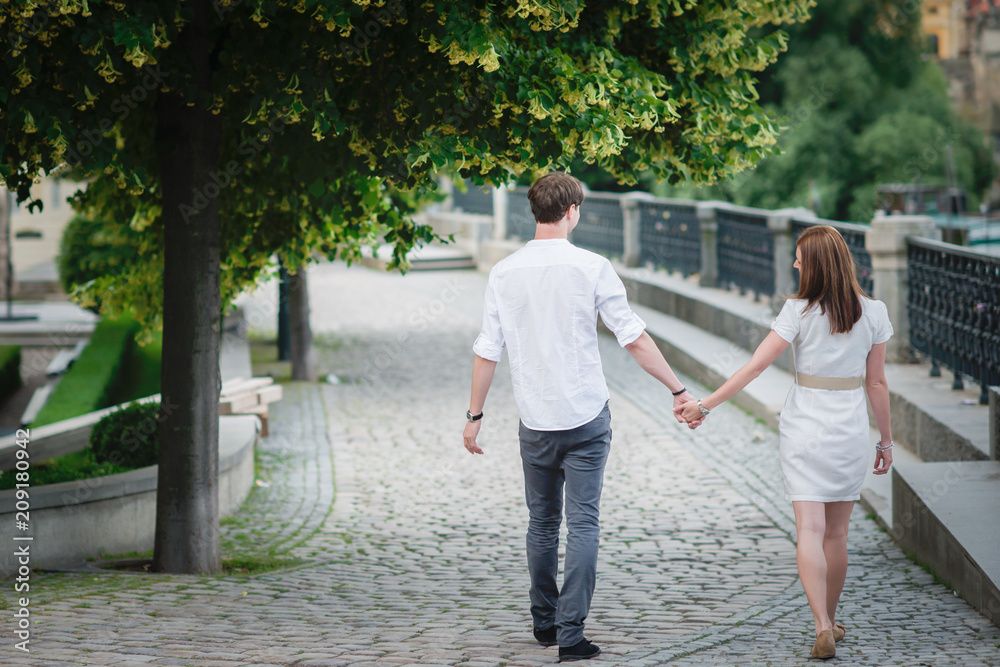 Obraz premium Young happy couple holding hands bridge in Prague