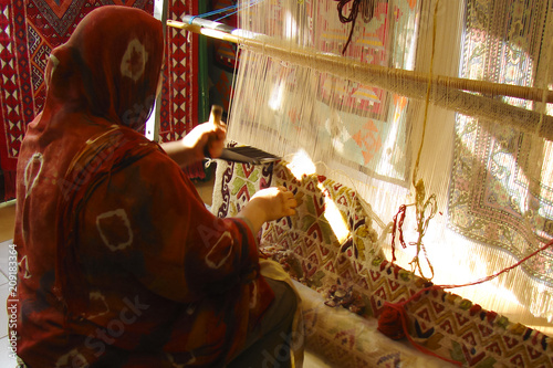 an old weaving workshop of traditional pile rugs (Kairouan, Tunisia); an Arab craftswoman making colorful wool carpet by hand