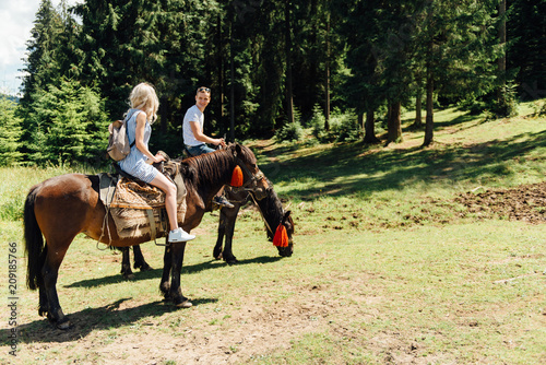 beautiful couple riding on horses in the mountains