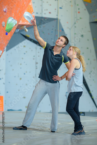 fit couple at the rock climbing wall at the gym