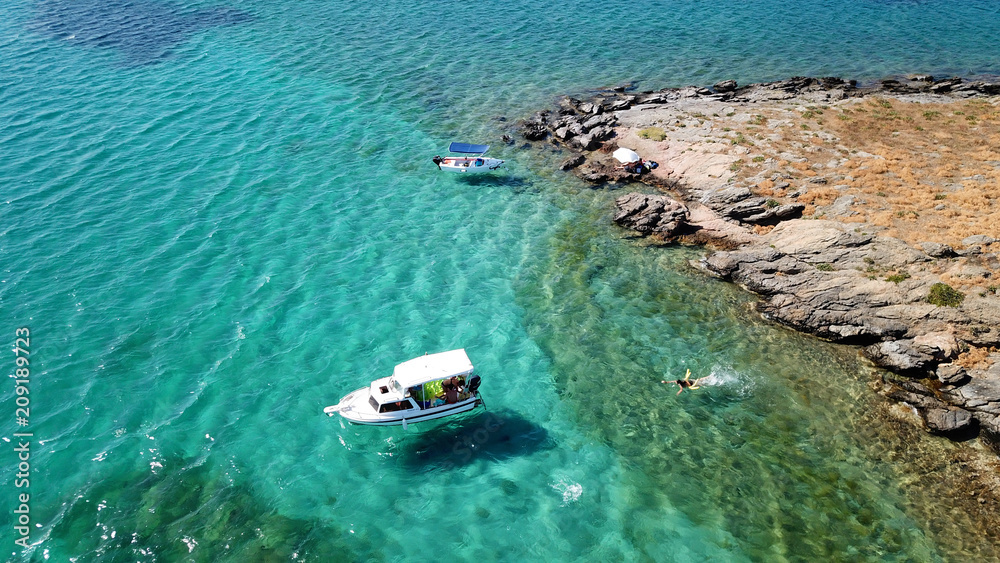 Fototapeta premium Aerial drone bird's eye view photo from boats docked in turquoise clear water rocky beach in island of Irakleia, Cyclades, Greece