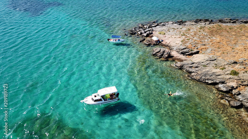 Aerial drone bird's eye view photo from boats docked in turquoise clear water rocky beach in island of Irakleia, Cyclades, Greece © aerial-drone