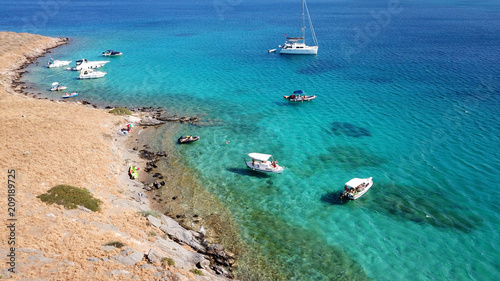 Aerial drone bird's eye view photo from boats docked in turquoise clear water rocky beach in island of Irakleia, Cyclades, Greece