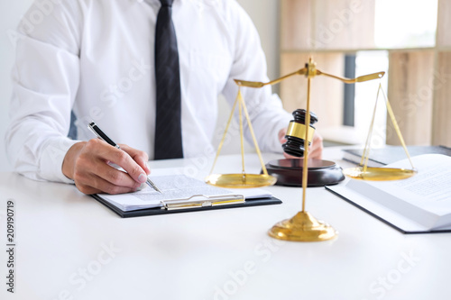 Businessman or lawyer working on a documents, judge gavel with Justice lawyers at law firm in background, Legal law, advice and justice concept