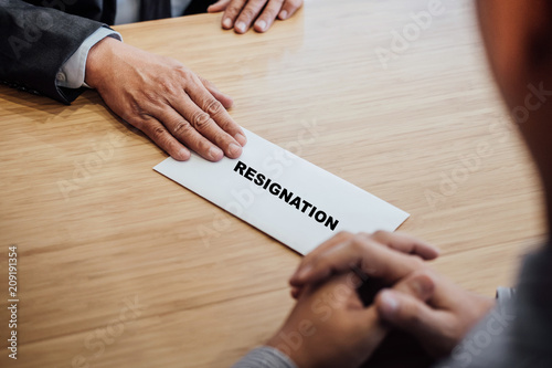 Hand of employer filing final remuneration to employee, letter of resignation, resign concept