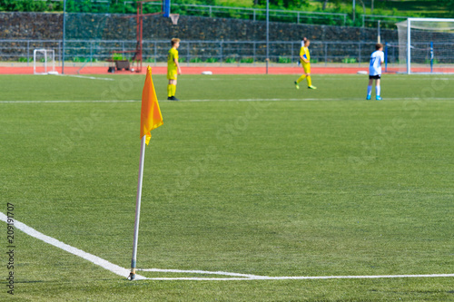 Yellow corner flag on the football field against a players in blur