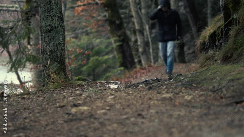 Tourist Concept - The Legs Of Unidentified Man In Jeans Walk Along The Trails Of A Hilly Autumnal Beautiful Forest Tourist Concept - The Legs Of Unidentified Man In Jeans Walk Along The Trails Of A Hilly Autumnal Beautiful Forest