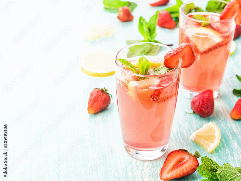 Glasses of a fresh pink lemonade. Strawberry soda with mint on a wooden table. Glasses of a fresh pink lemonade. Strawberry soda with mint on a wooden table.