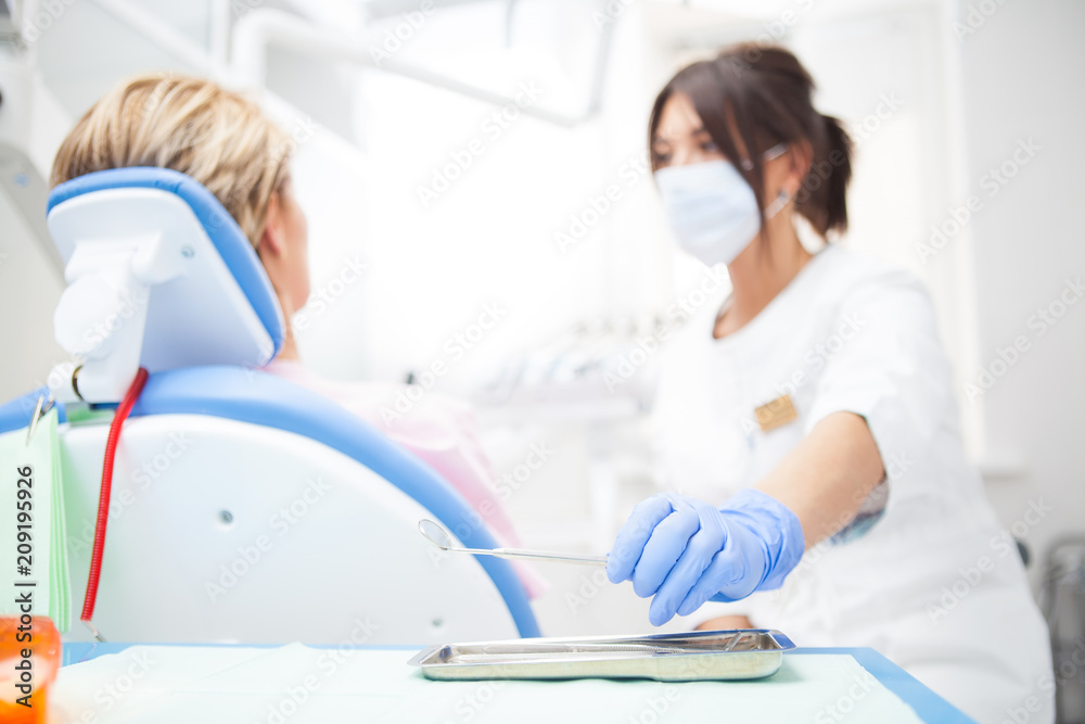 Fototapeta premium A close-up photo of a dentist's hand taking a sterile instrument from a metal tray. Focus on the doctor's hand
