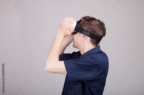 Excited man experiencing virtual reality for the firts time. He is wearing a VR headset. Gray background. Studio photo photo