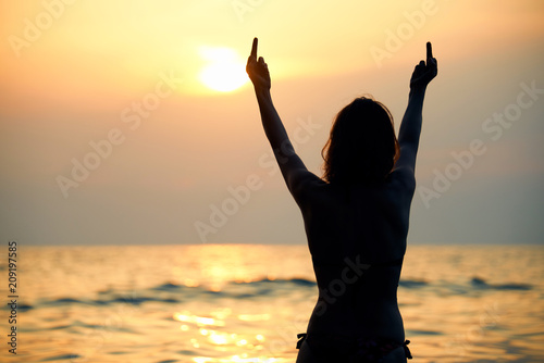 Young Female hand shows the sign of Fuck you in the summer sunset. 