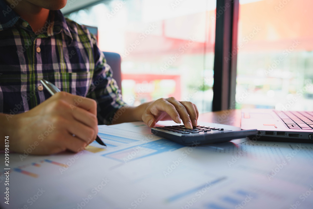 Obraz premium Businessman or accountant using pen and calculator for audit budget and finance of company on wooden desk in office.Auditor financial or bookkeeper concept.