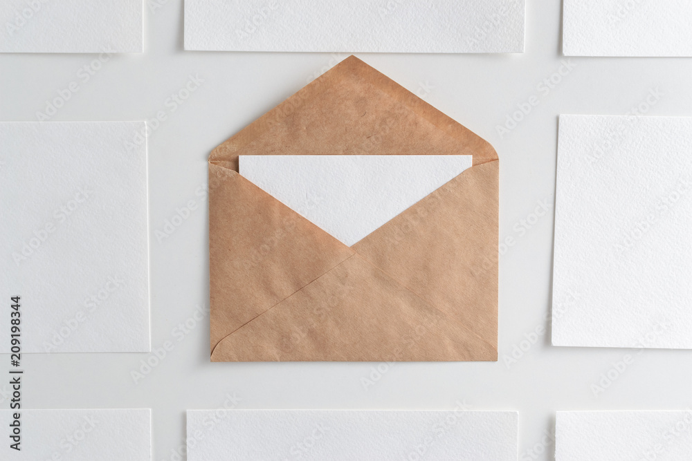 Mockup of horizontal business cards stacks arranged in rows and craft envelope in center at white textured background. Mockup of horizontal business cards stacks arranged in rows and craft envelope in center at white textured background.