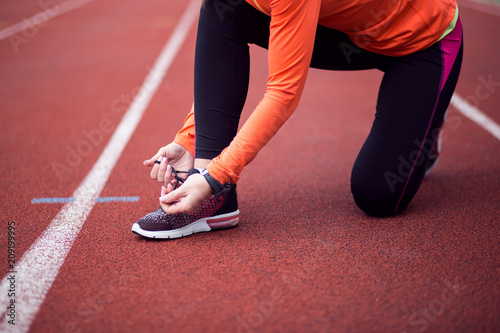 Woman runner tying shoelaces with copy space