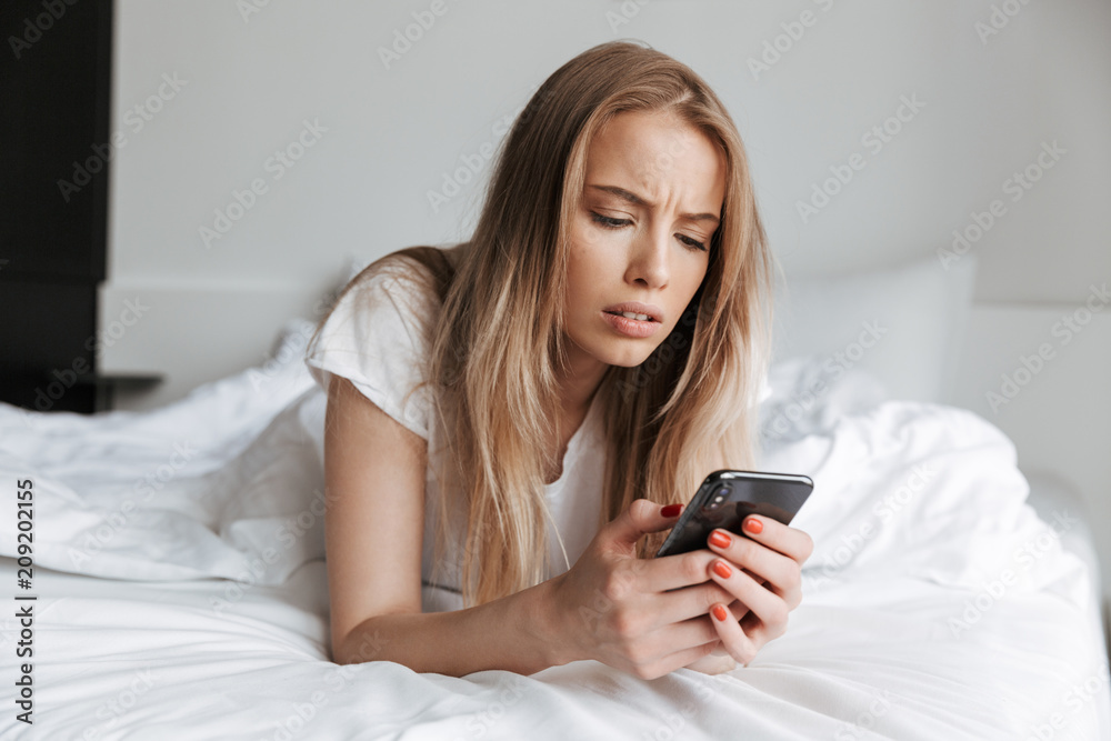 Sad woman lies on bed indoors at home Sad woman lies on bed indoors at home