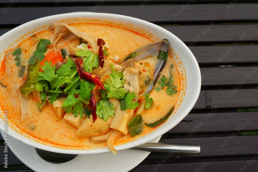 Thai food style (Tom Yam seafood), Thai food in white bowl on wooden table, top view, Space for text in template. This food is most popular Thai food. Thai food style (Tom Yam seafood), Thai food in white bowl on wooden table, top view, Space for text in template. This food is most popular Thai food.