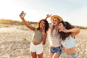 Three smiling girls friends in summer clothes