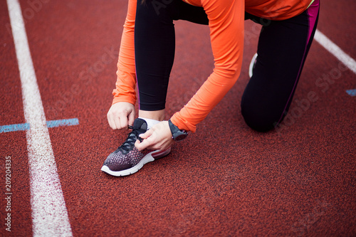 Woman runner tying shoelaces with copy space