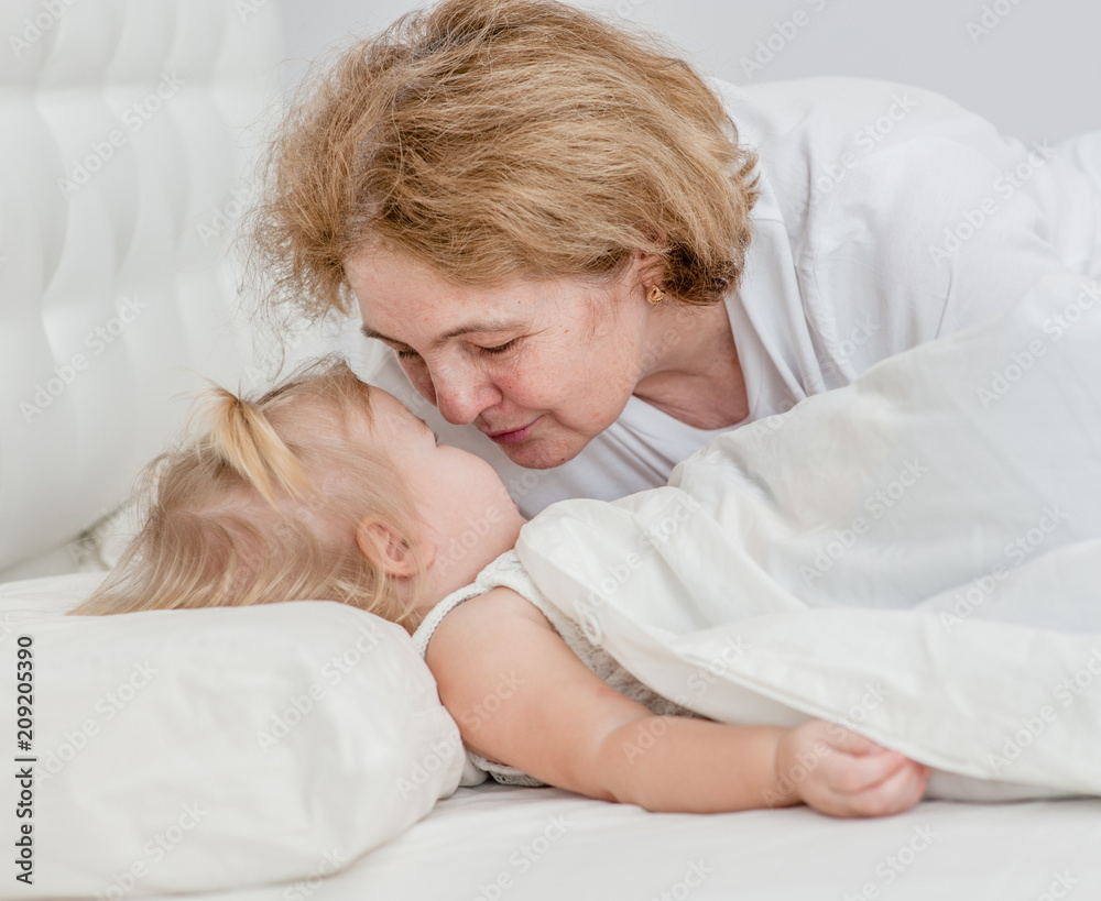 grandmother kisses granddaughter before bedtime grandmother kisses granddaughter before bedtime