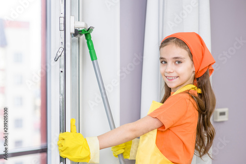 Smiling girl cleaning window with swab