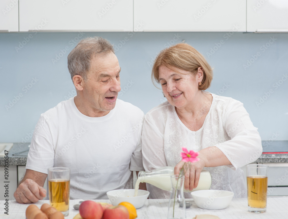 Smiling elderly couple having breakfast in the kitchen of the house