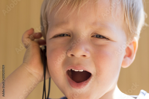 Close-up portrait of cute toddler boy with ear-phones listening music
